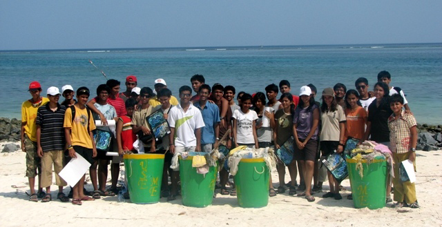 Young men and women with bags of trash collected from beach on Kavaratti Island, India