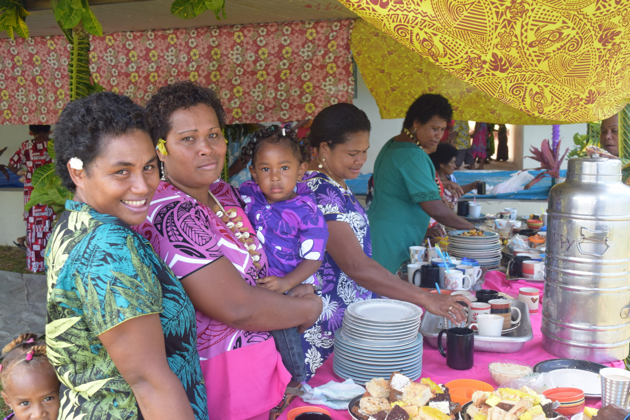 Women and children enjoy a meal in brightly decorated building