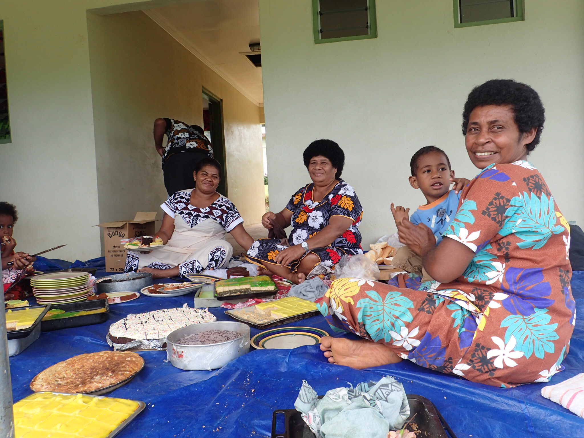 Women and children enjoy a meal in brightly decorated building