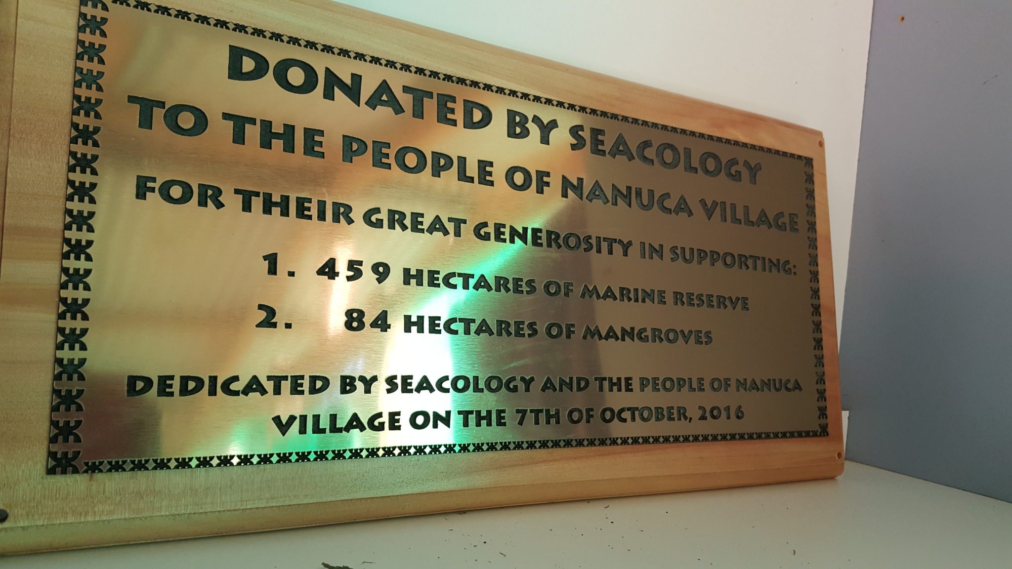 A metal plaque explaining Seacology's role in funding Nanuca's community hall