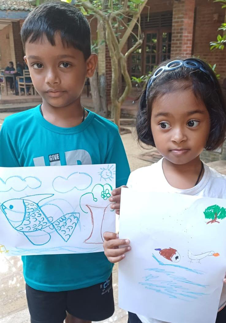 Two kids hold drawings of mangroves