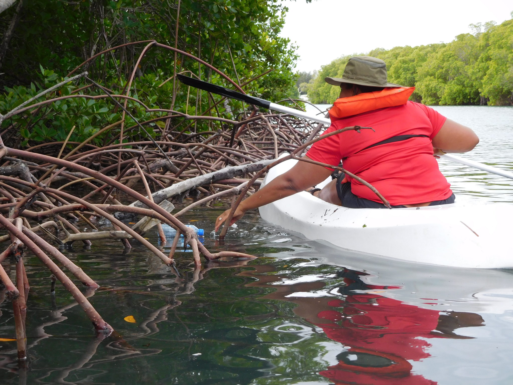 From a kayak, a woman picks up trash In Montecristi, Dominican Republic