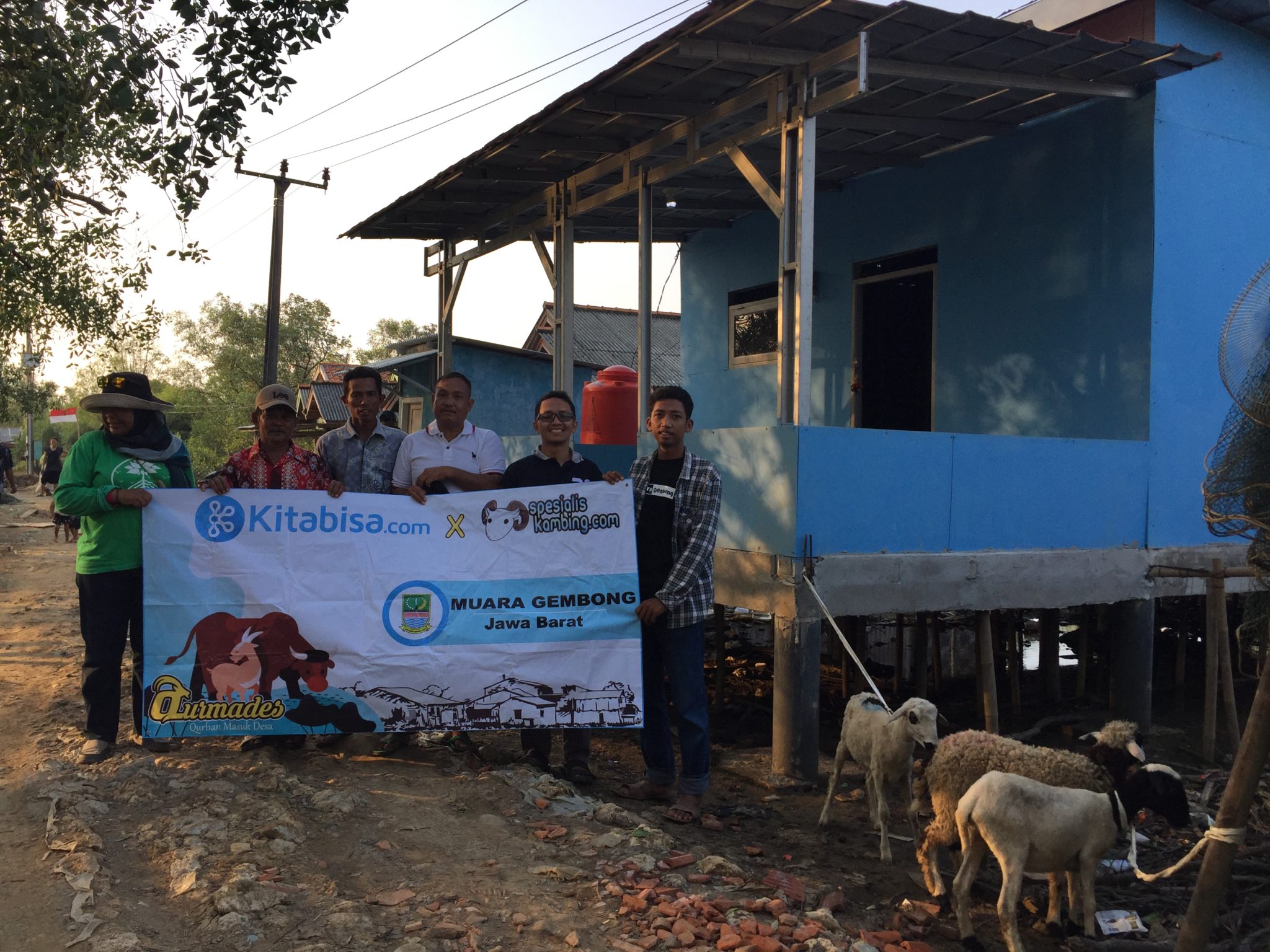 Community members with a sign that says "We can" outside the new community center in Panthai Bahagia, Indonesia