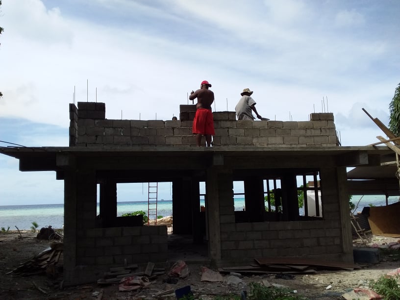 Men work on a partially built ranger station on Kuop Atoll in Micronesia