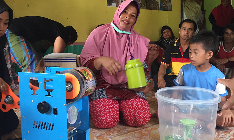 Woman showing fruit juice processing equipment in West Kalimantan, Indonesia village