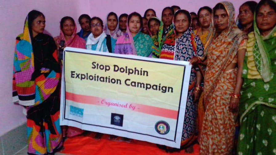 Indian women in saris hold a sign urging protection of dolphins in Chilika Lake