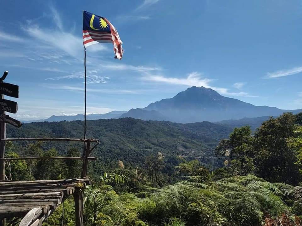 A Malaysian flag flies, with Mt. Kinabalu in the distance, along a hiking route near Rungus Nahaba