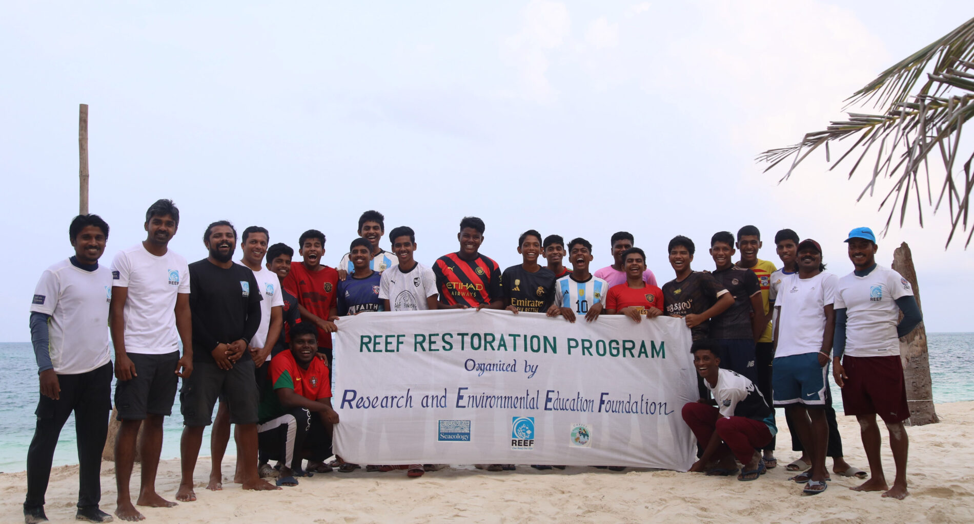 Group of people on beach with Reef Restoration Program banner