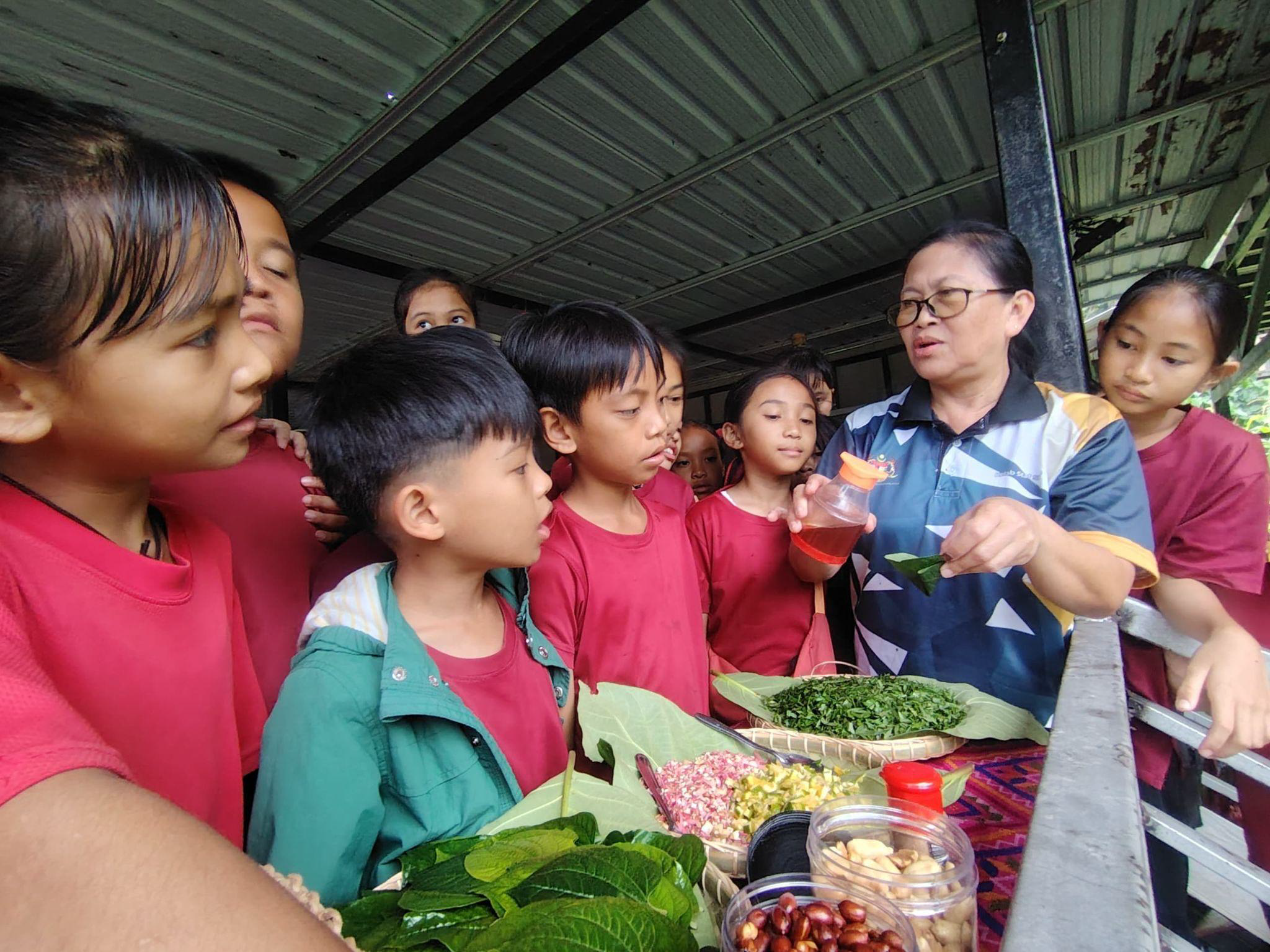 A woman shows frresh produce to a group of kids