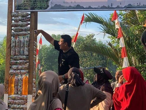 A person points out a sculpture made of old plastic bottles to a group of people who are watching