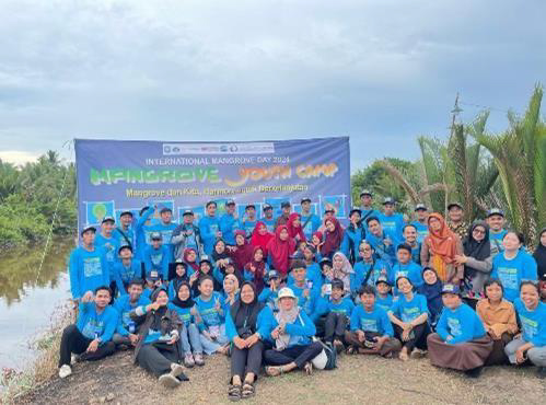 A group of people in blue shirts poses together in front of a banner