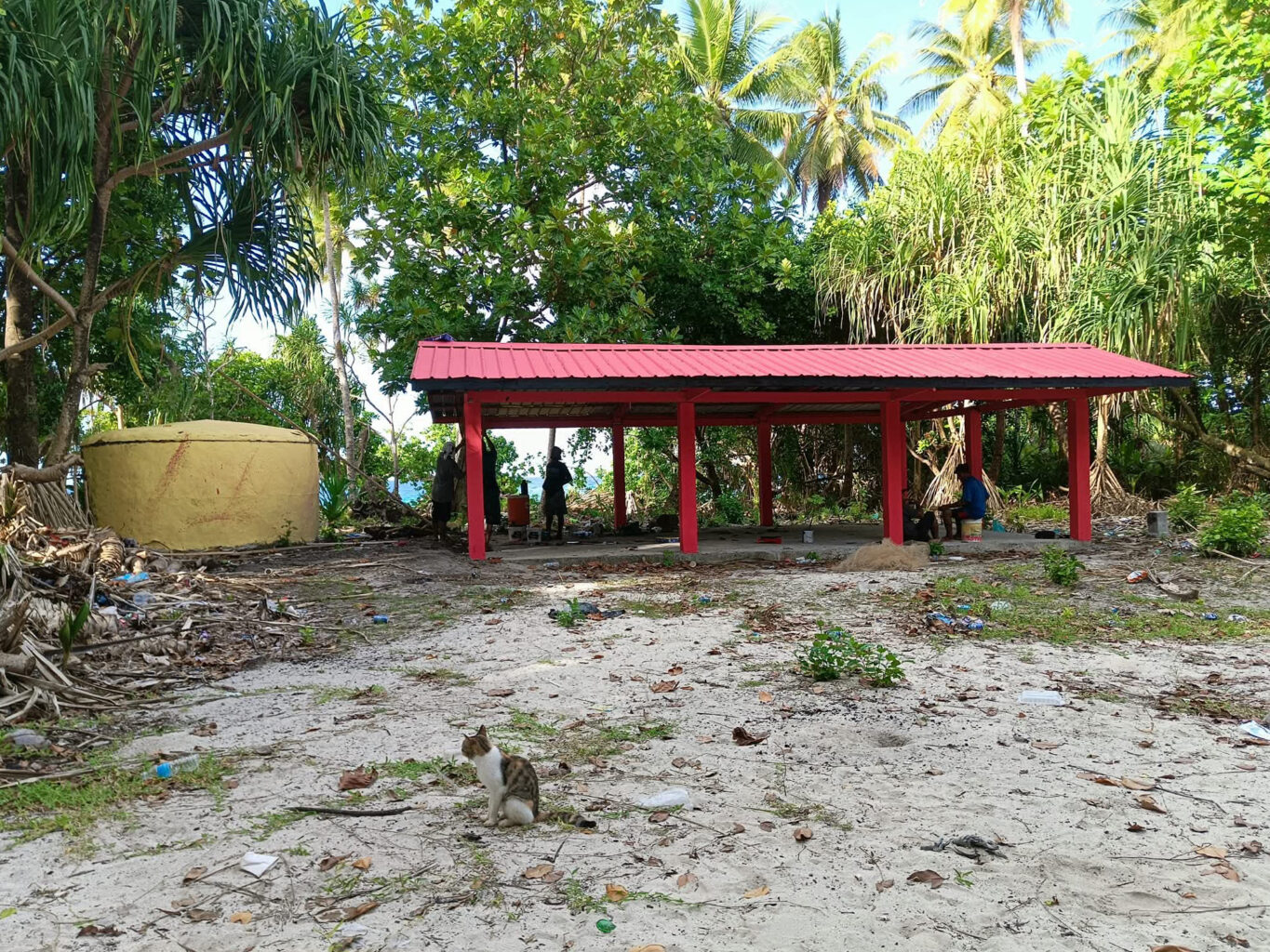 Red canopy structure on shoreline with trees and ocean in background
