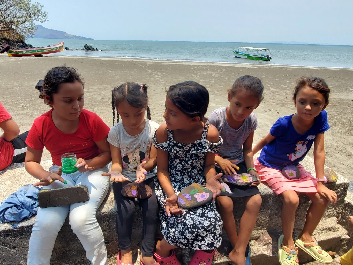 Young children use finger paint while sitting on a bench