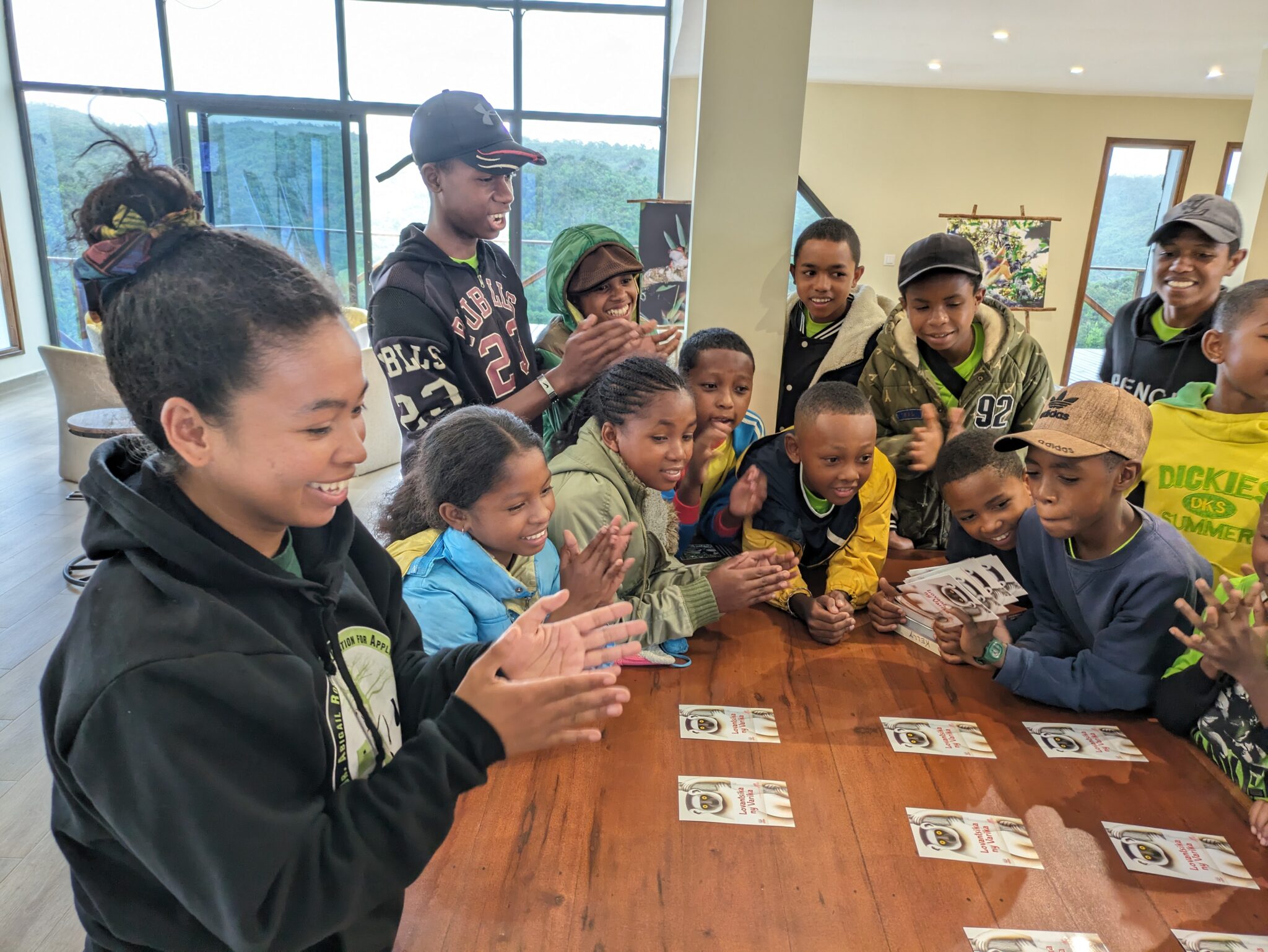A group of kids gathers around a table looking at printed cards