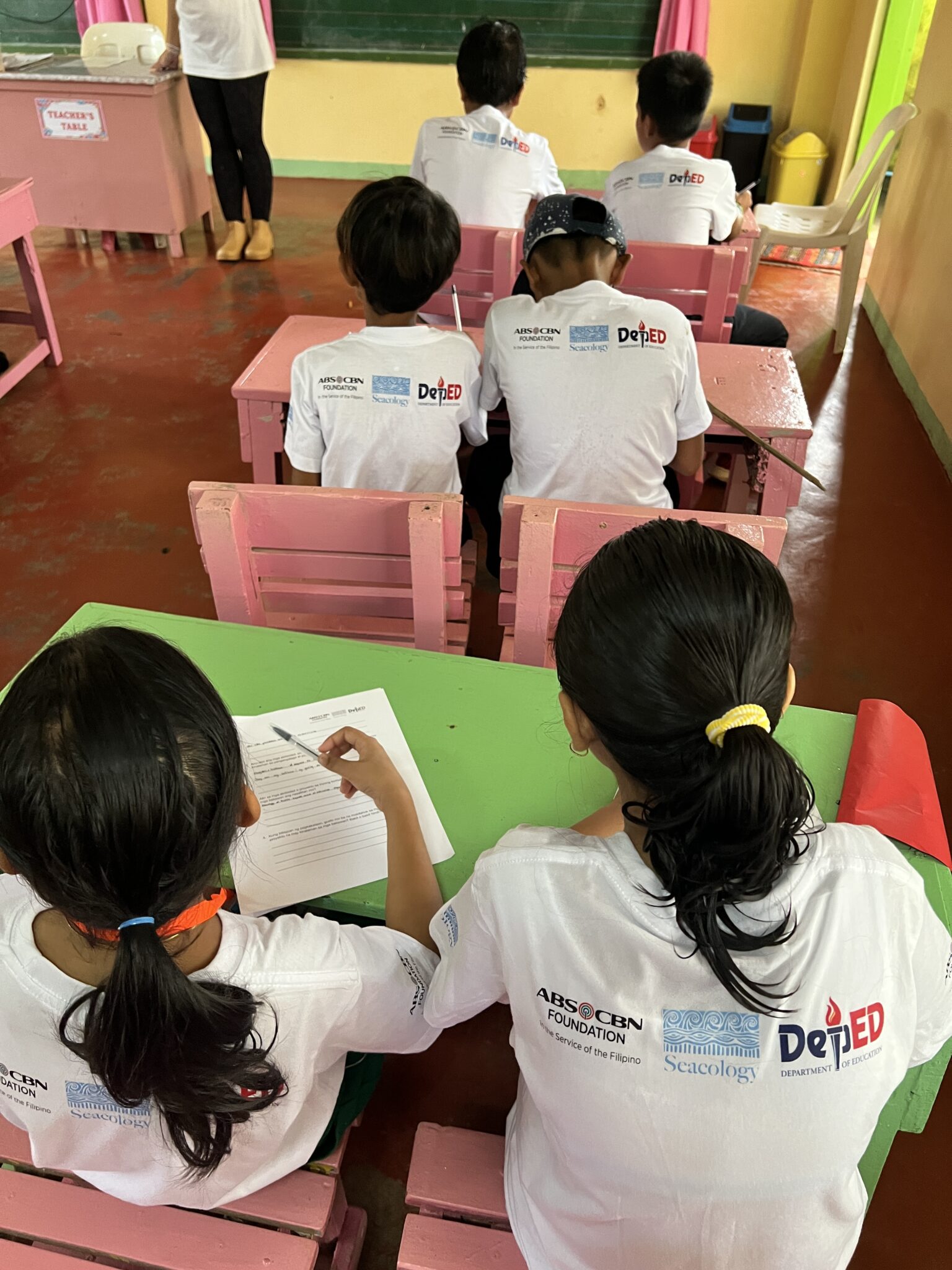 Kids studying in classroom, seen from behind