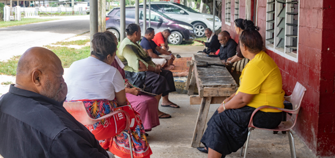 A group of people sit in discussion on a porch