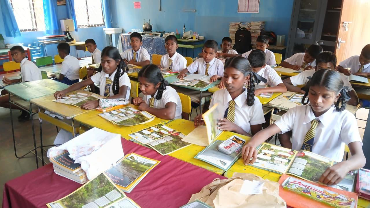 A group of students sit at desks with conservation learning materials