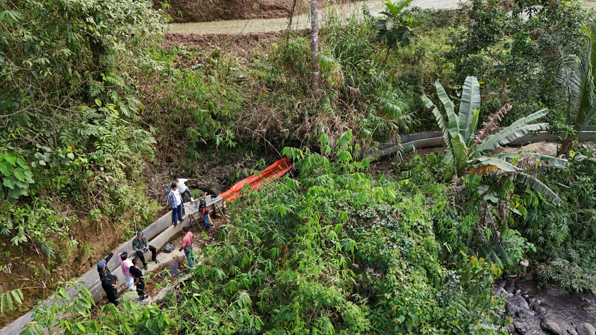 drone shot of a couple of people standing next to concrete water channel