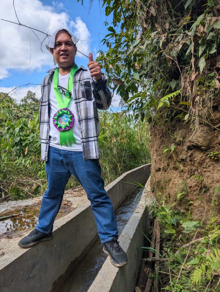 A community member stands over the new canal that feeds the micro-hydro system.