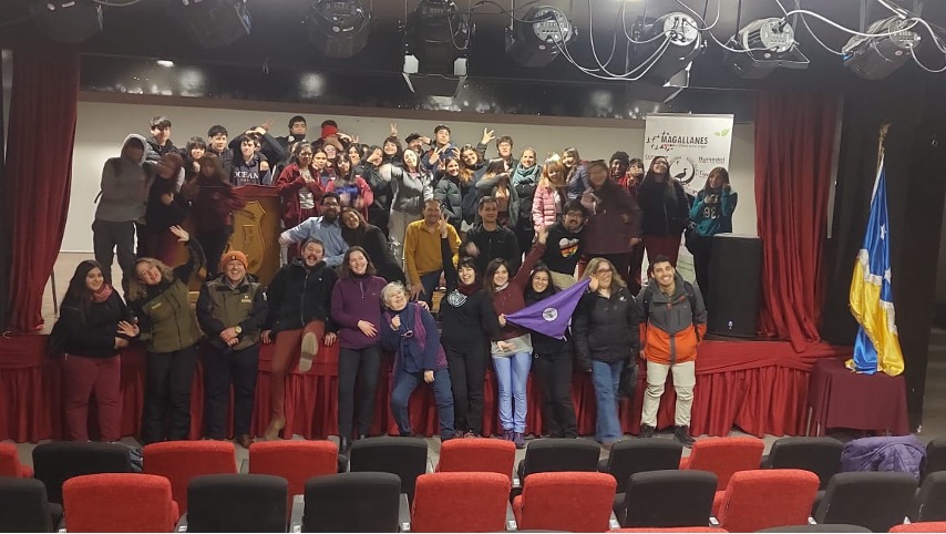A large group of people poses in an auditorium