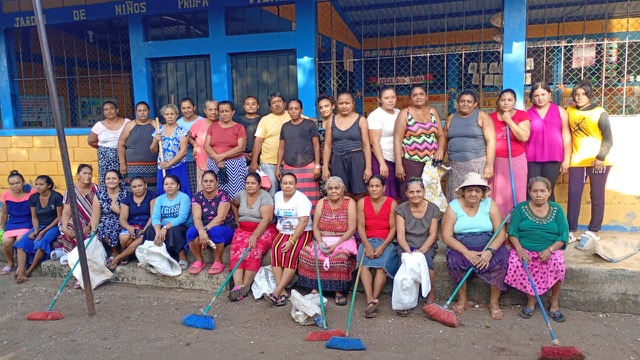A group of people pose with mops in front of a colorful building