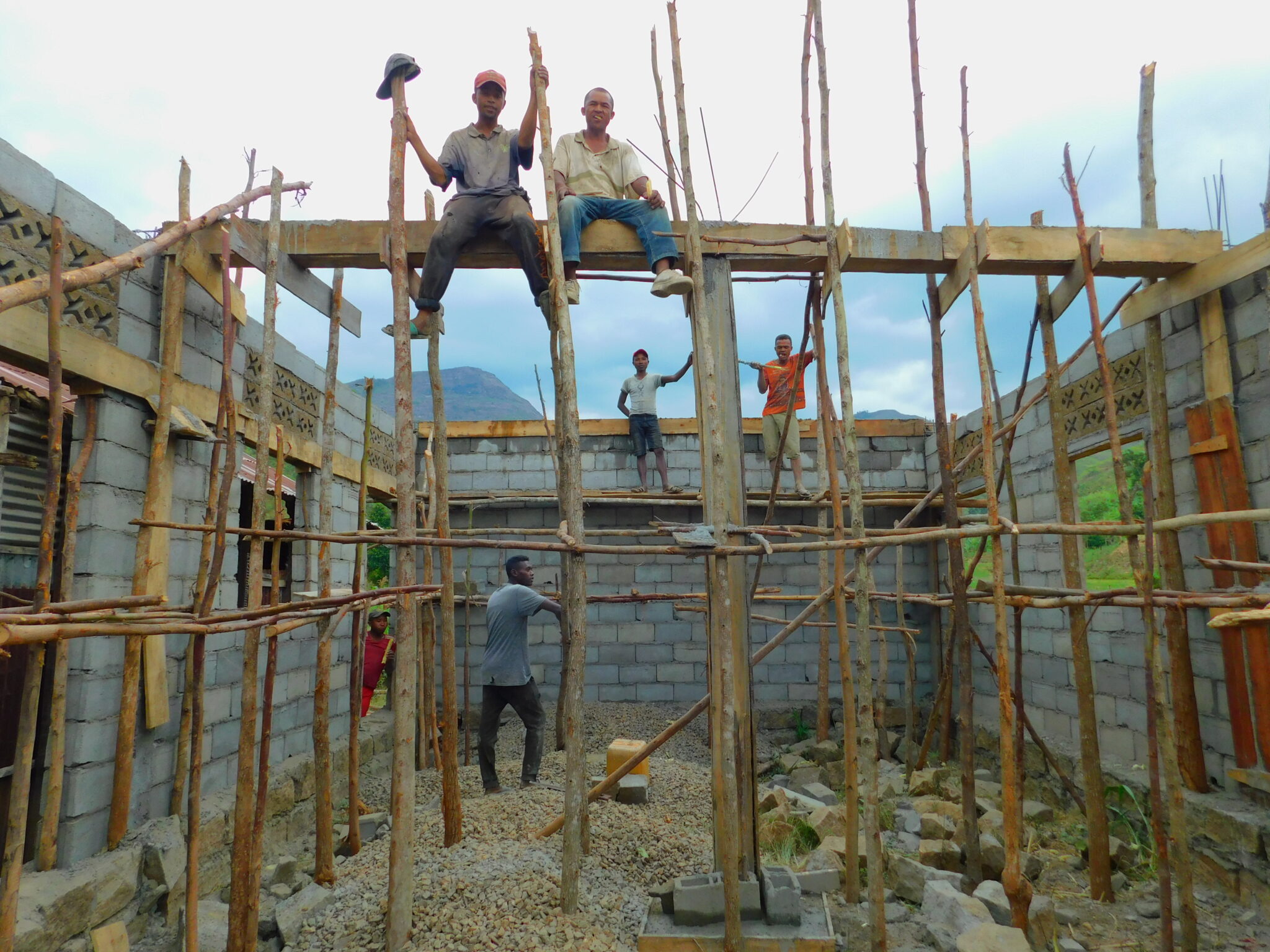 A group of people sit on scaffolding around a building in the process of being constructed