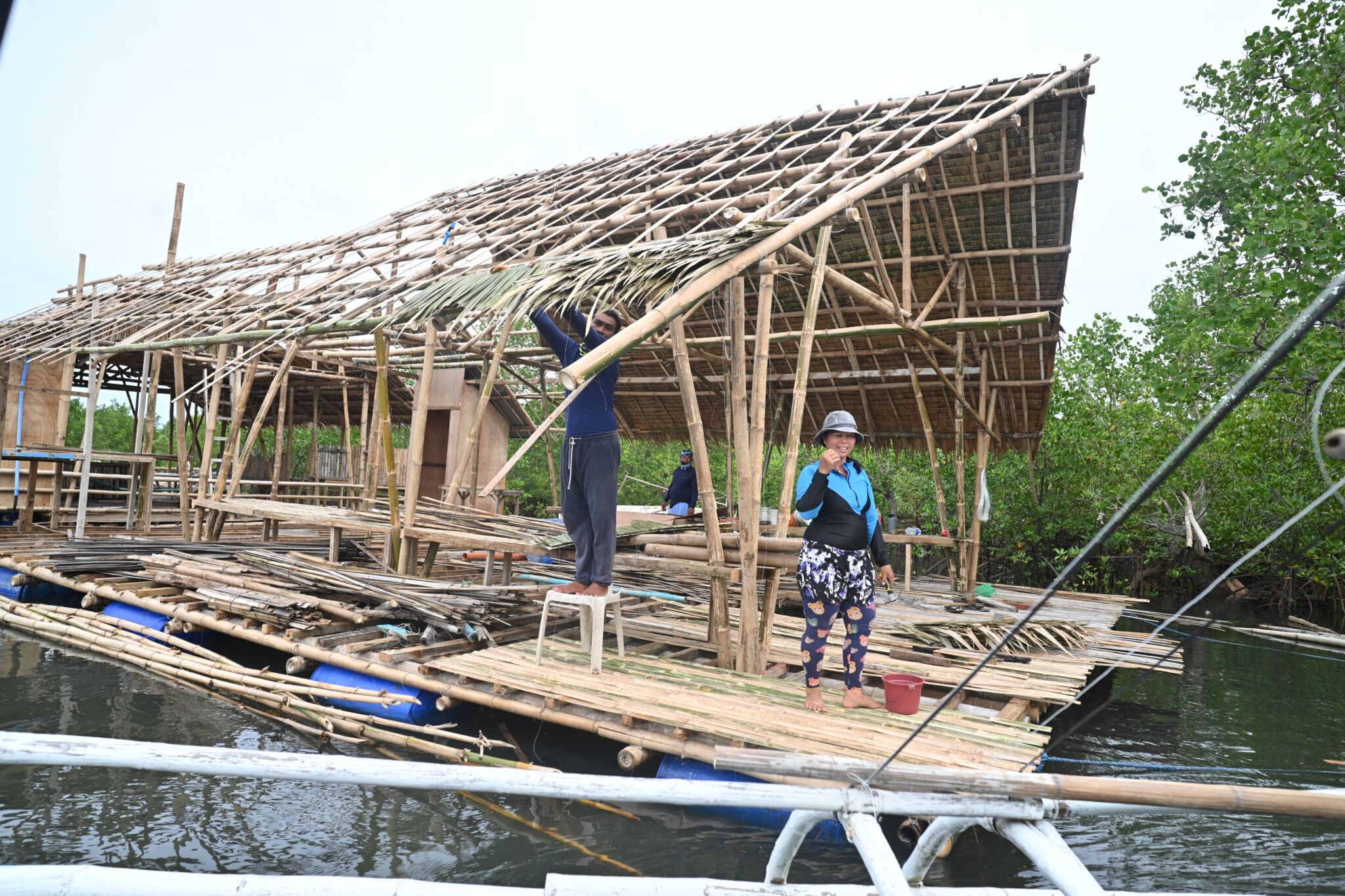 two workers fix roof of floating cabin under construction
