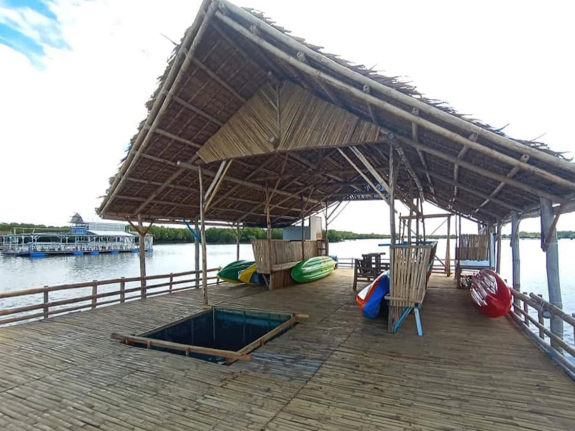A large wooden building with kayaking equipment floats on the water