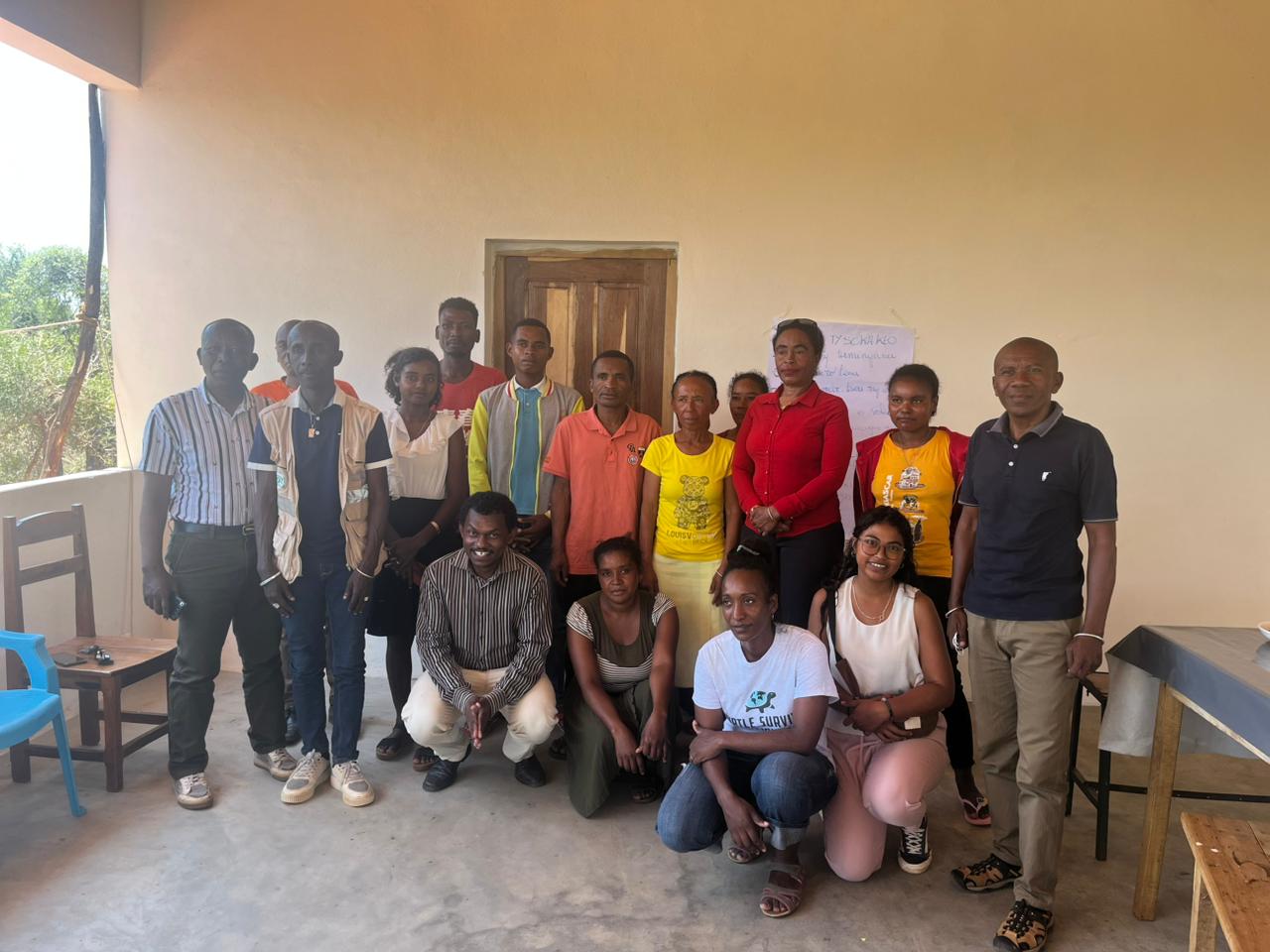 A group of people pose for the camera in front of a school building