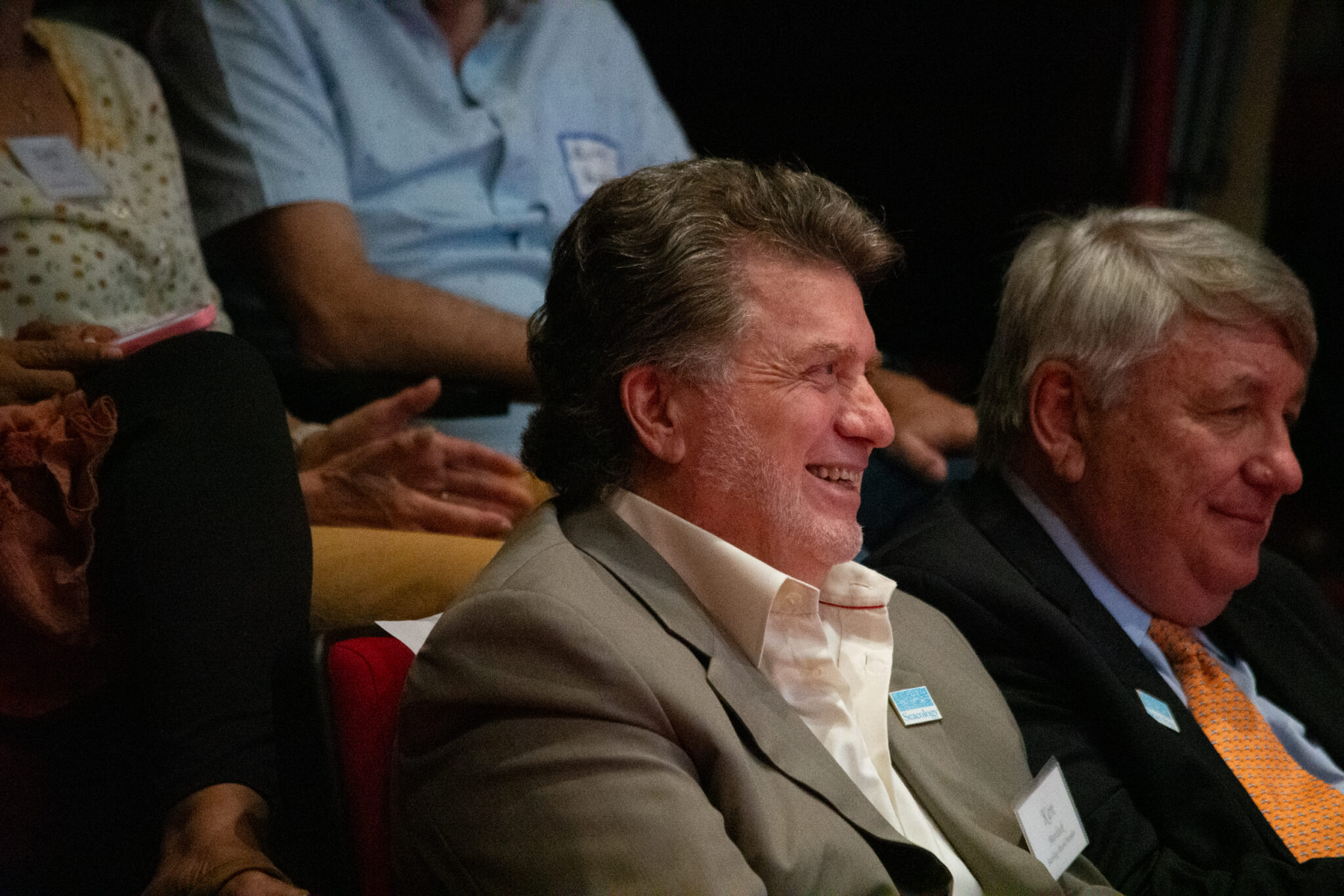 Two men sit in front row of theater