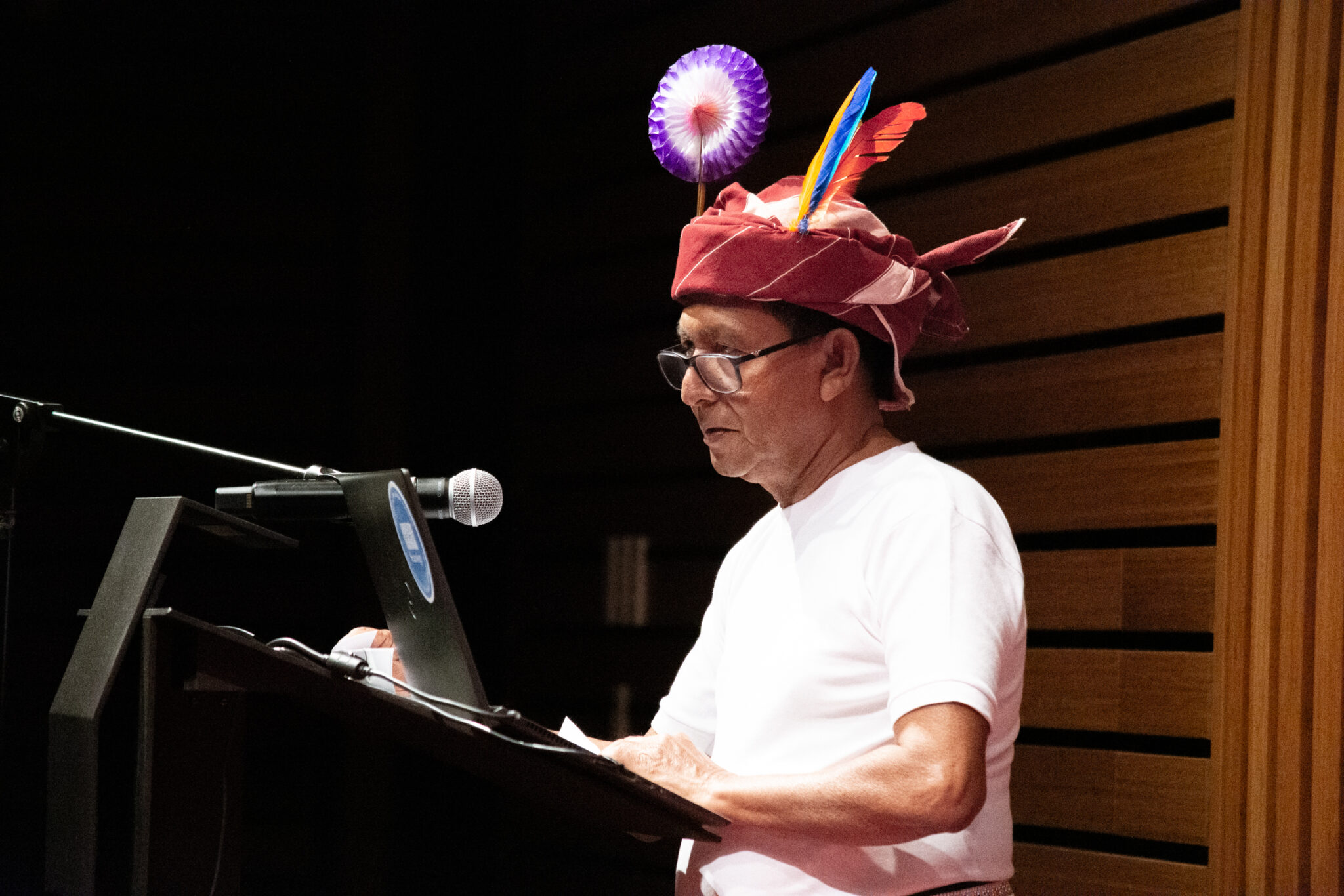 Man wearing traditional head wrap speaks at podium