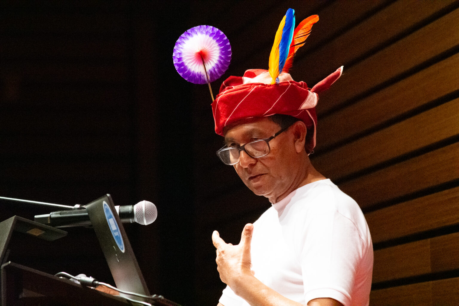 Man wearing traditional head wrap speaks at podium
