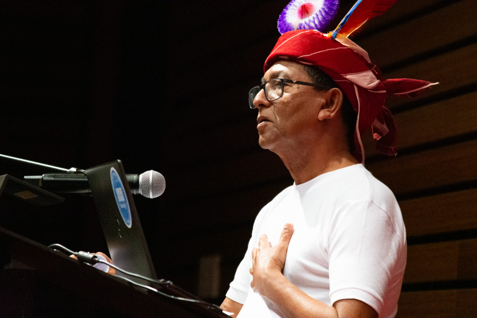Man wearing traditional head wrap speaks at podium