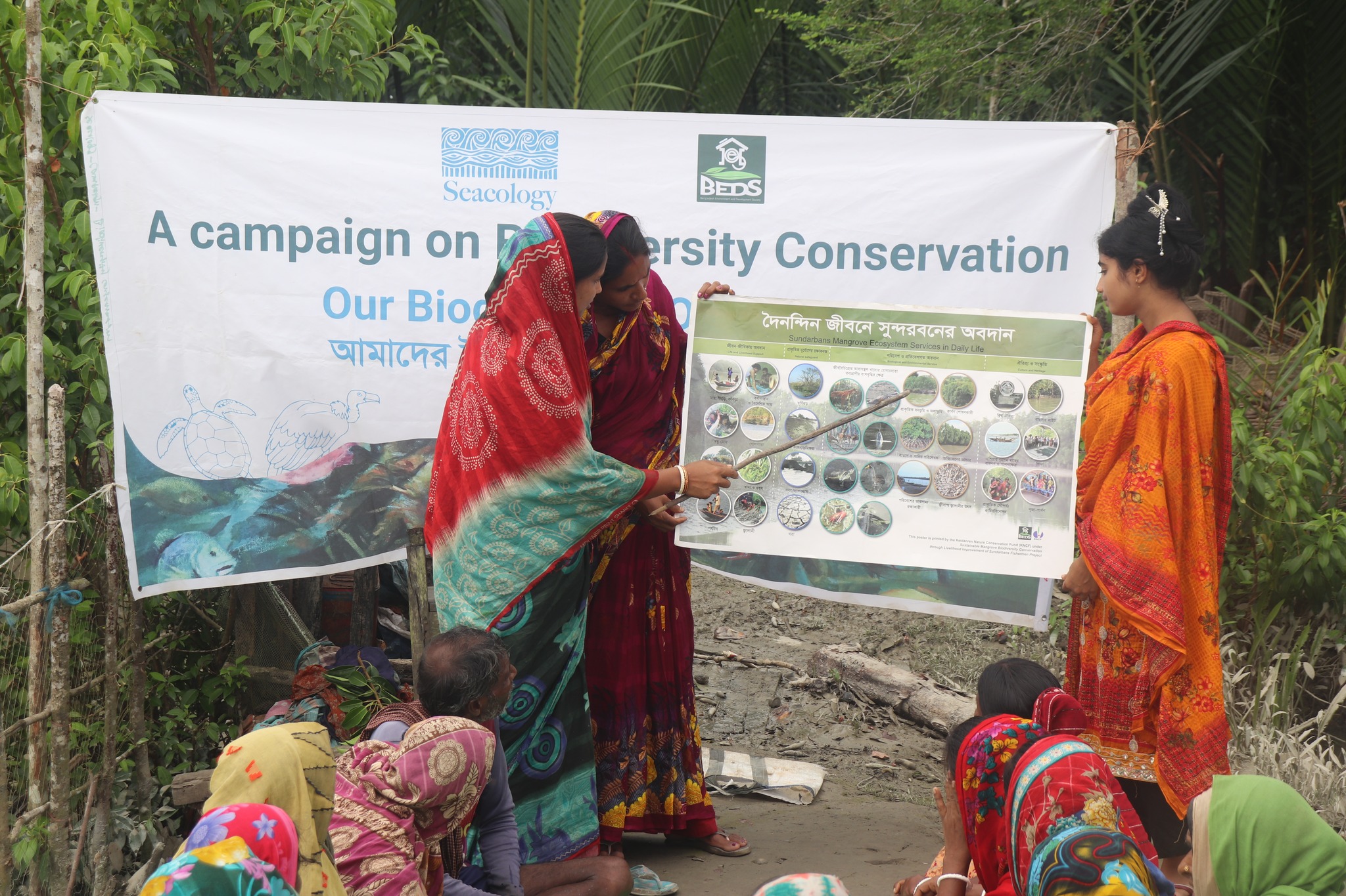 Group of people sitting on ground outside and watch presentation
