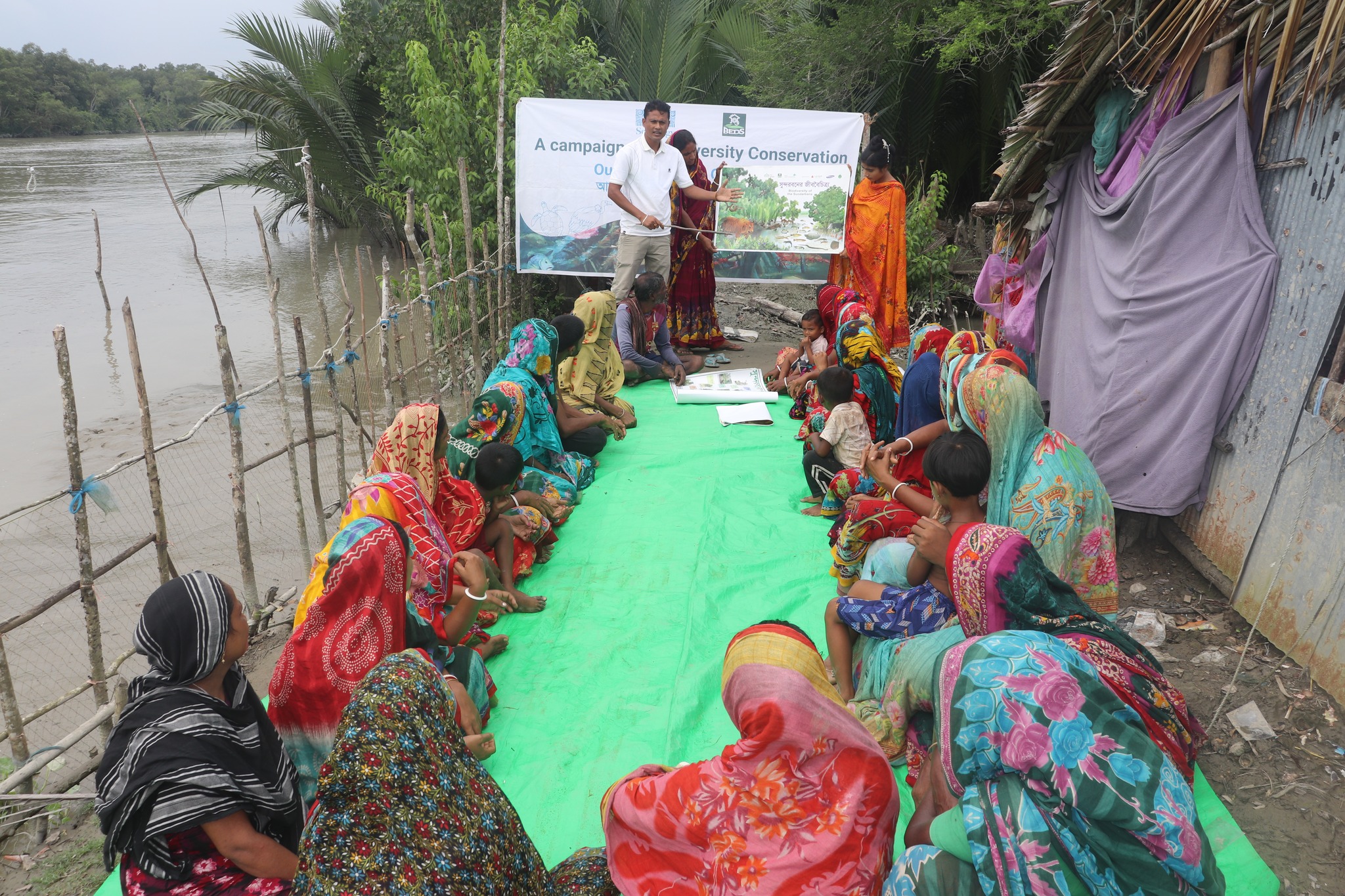 Group of people sitting on ground outside and watch presentation