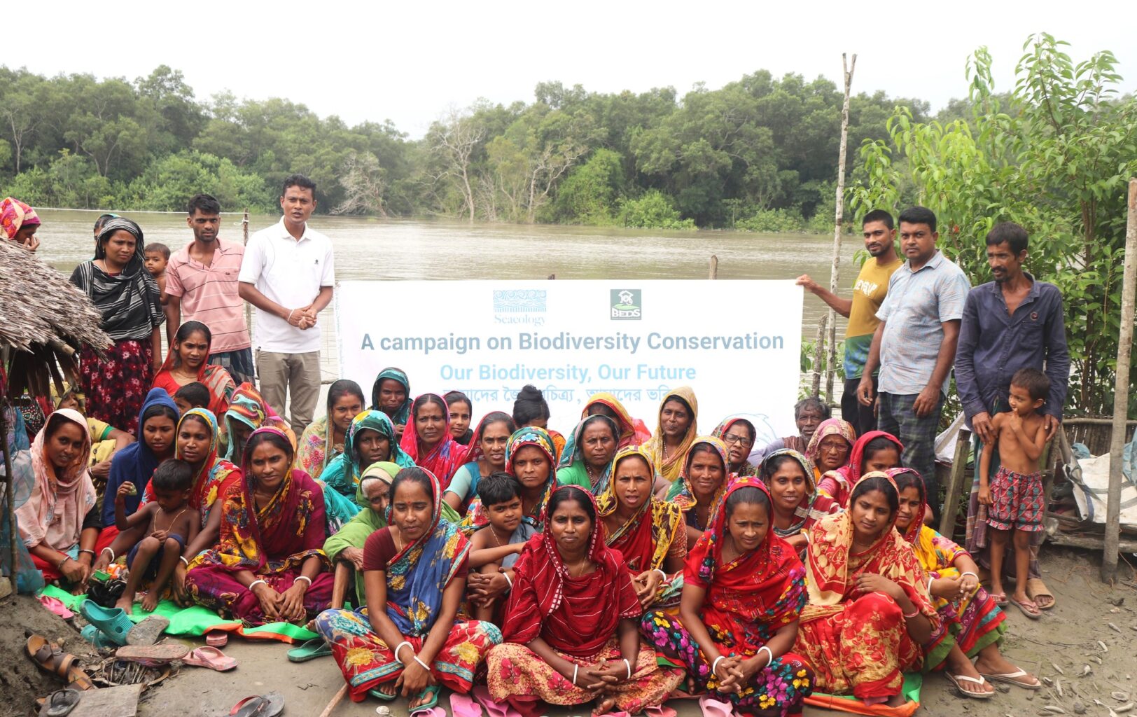 Group of people sitting on ground outside and watch presentation