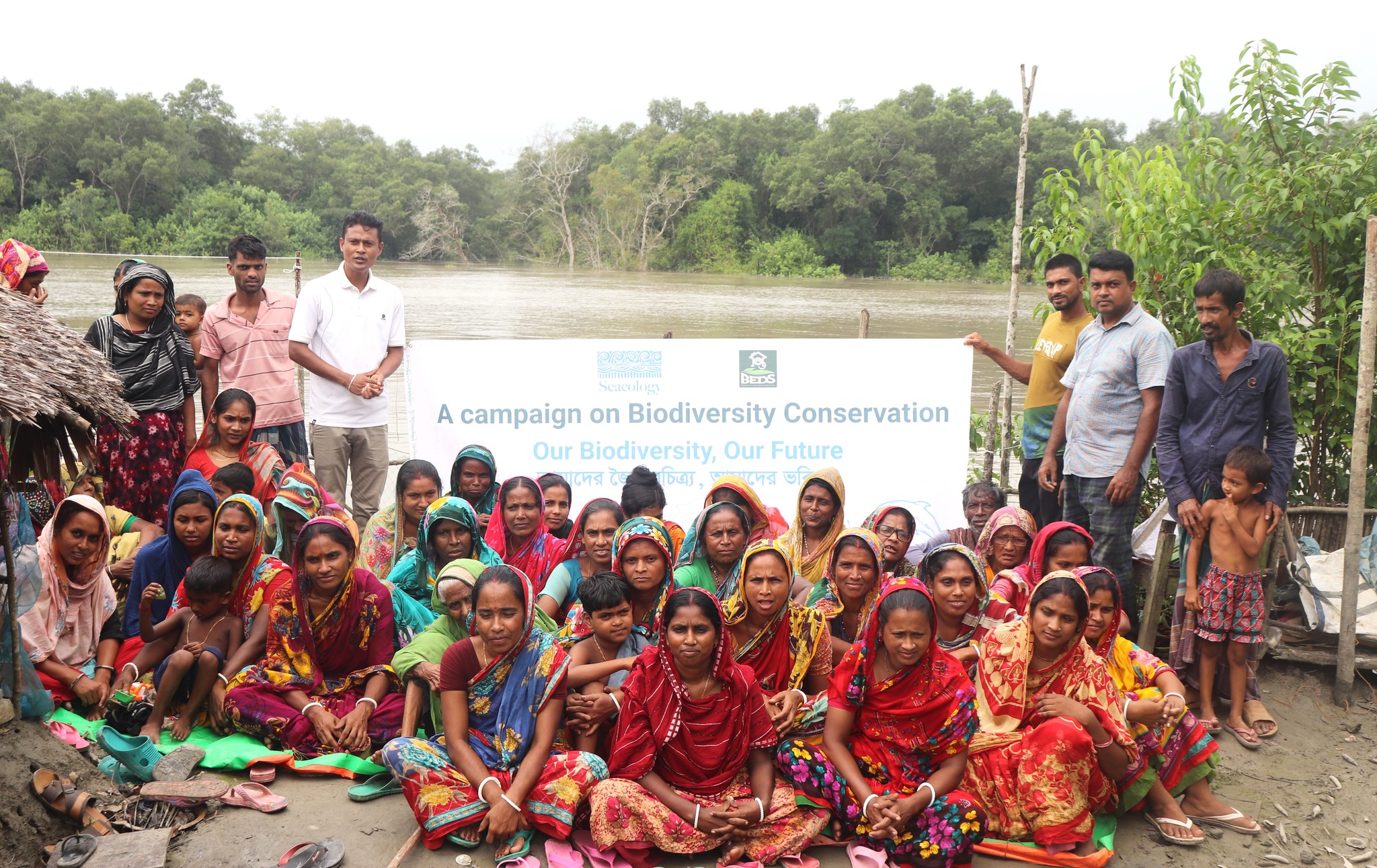 Group of people sitting on ground outside and watch presentation