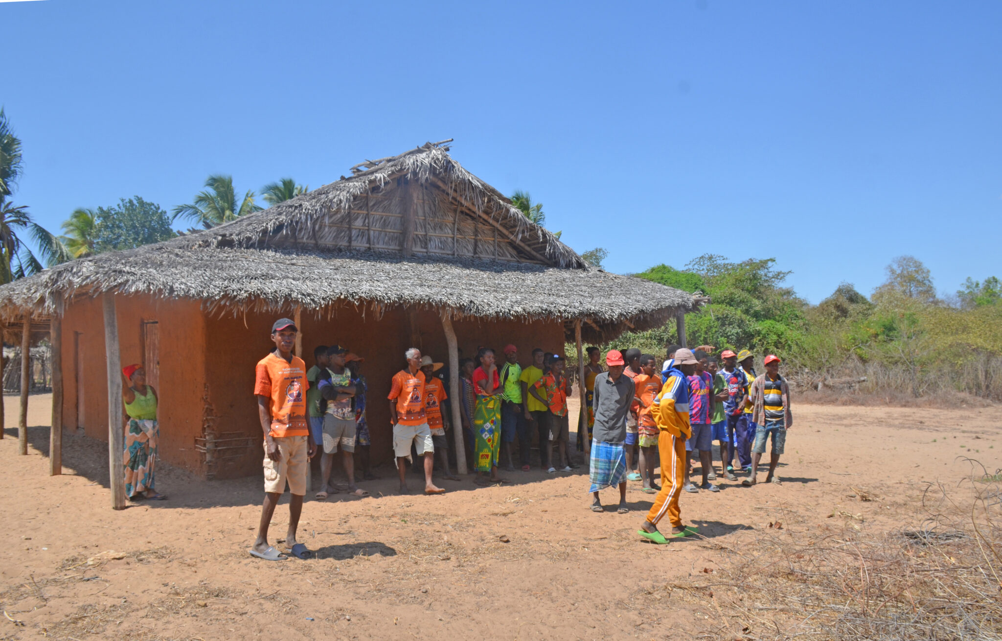 Community members stand outside dilapidated building