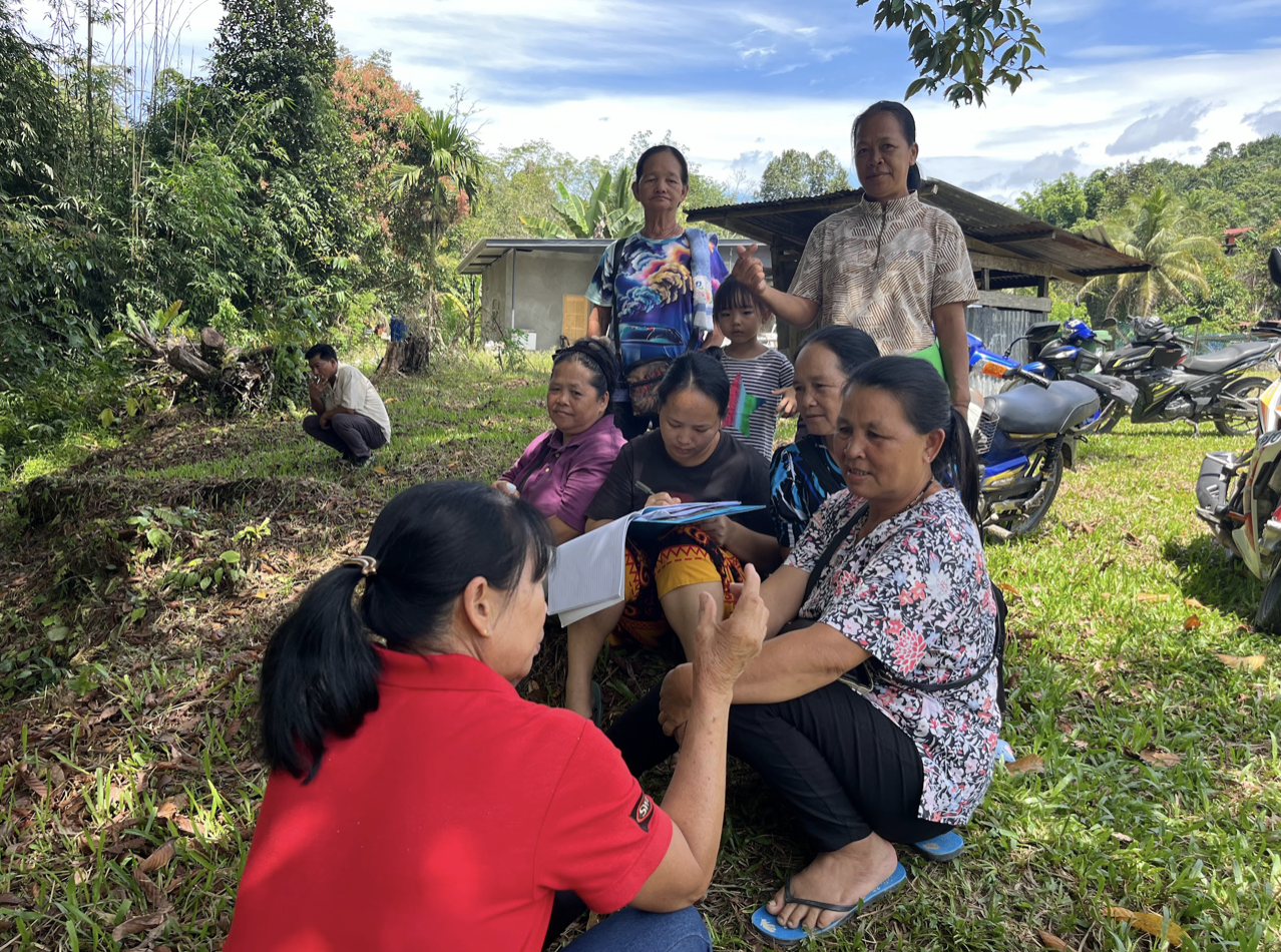 Group of people sitting on ground sign papers