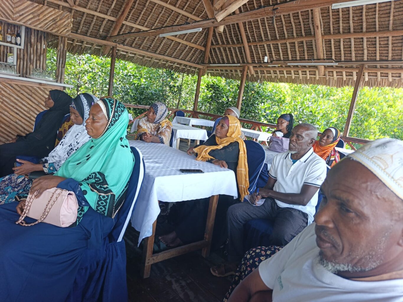 group of people sit in covered outdoor classroom