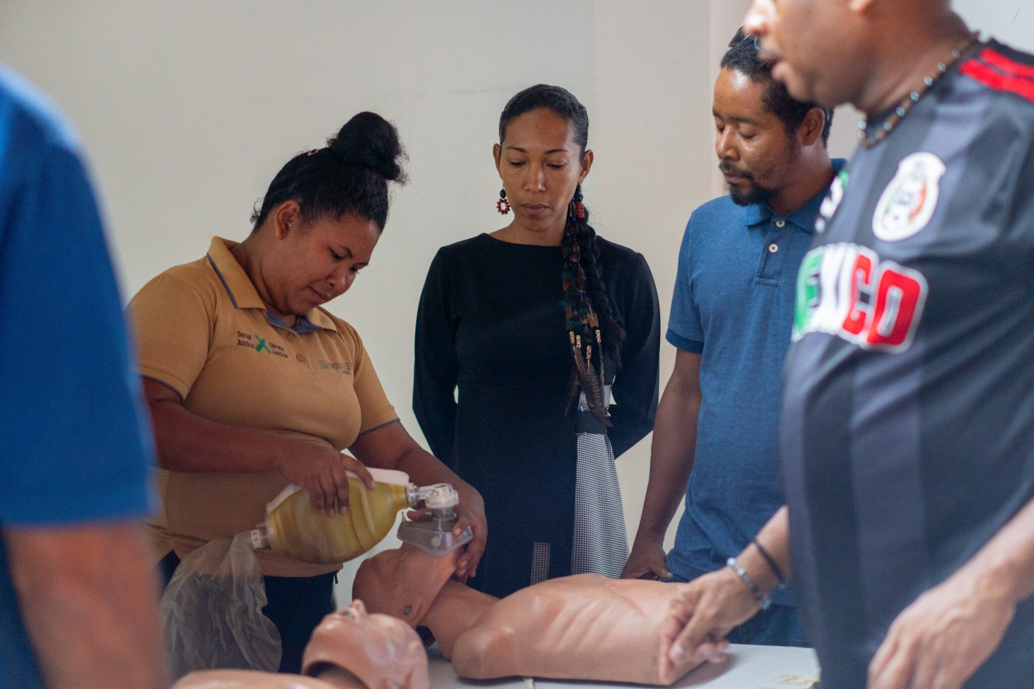 Group of people practices first aid with a CPR dummy