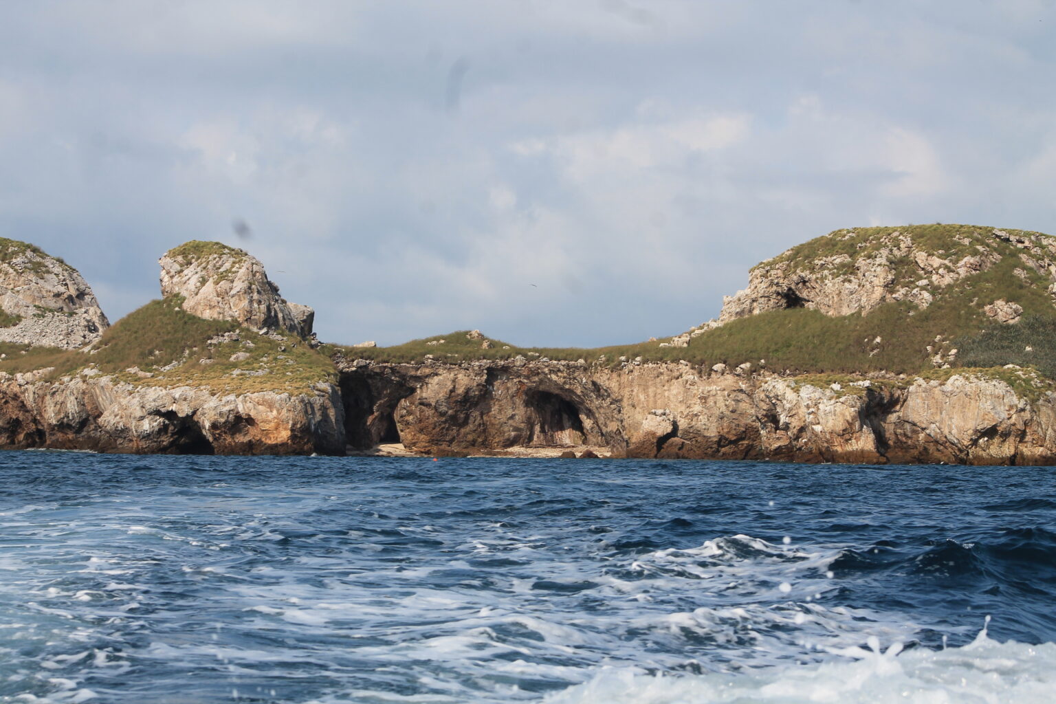 Open water with island in background, showing cliffs and green plateau