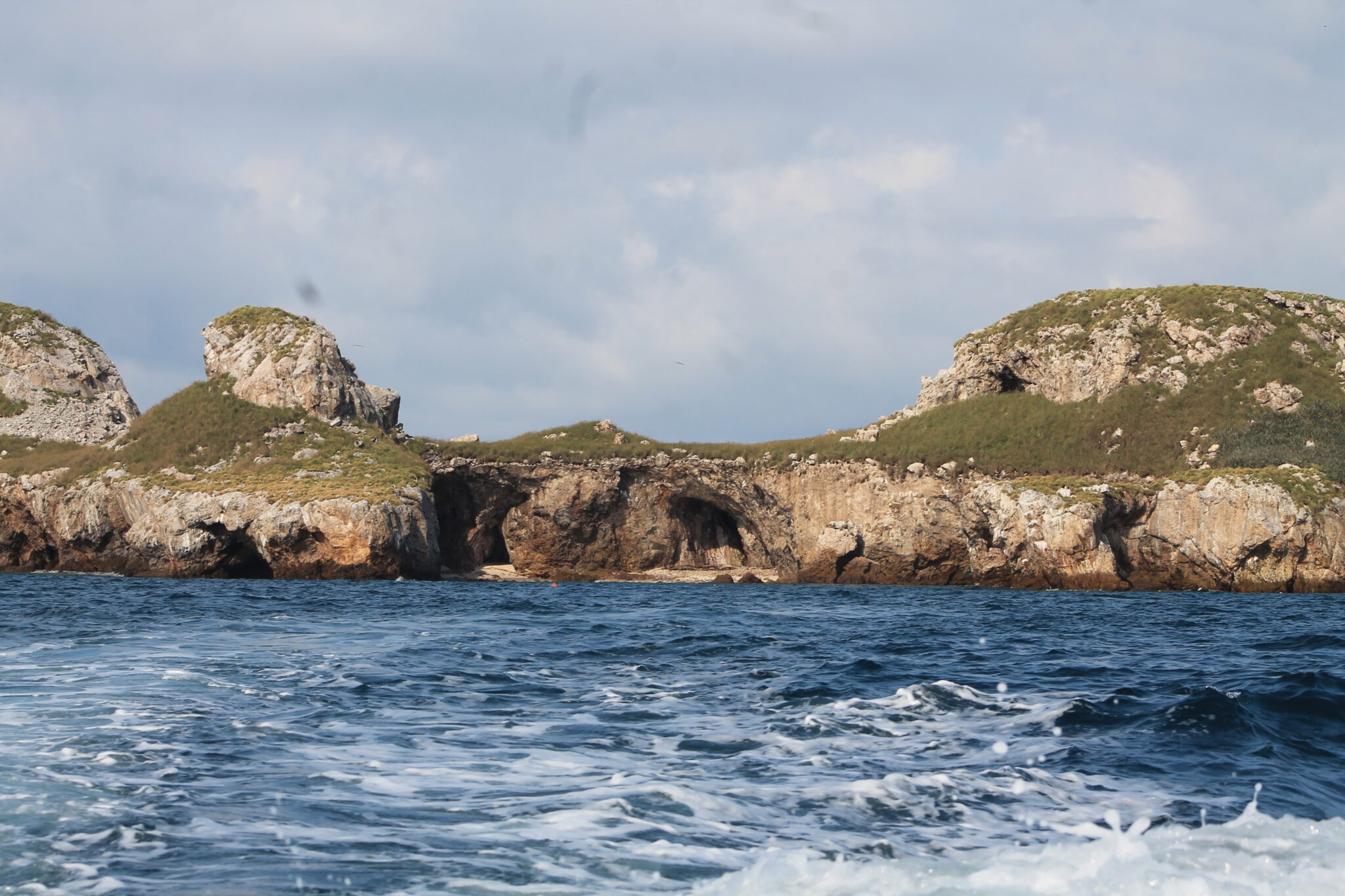Open water with island in background, showing cliffs and green plateau