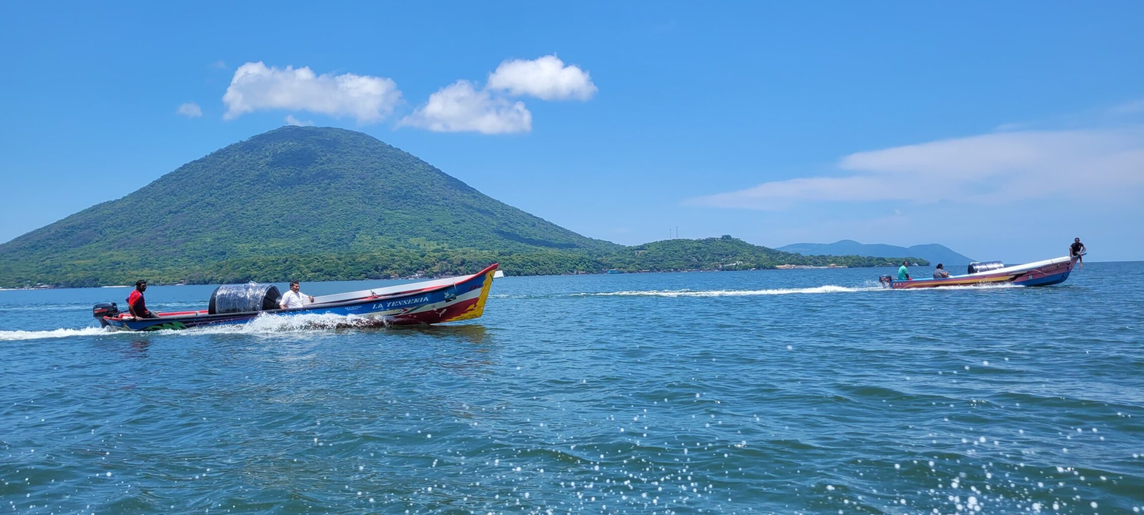 Two colorful boats on the water with a green island in the background