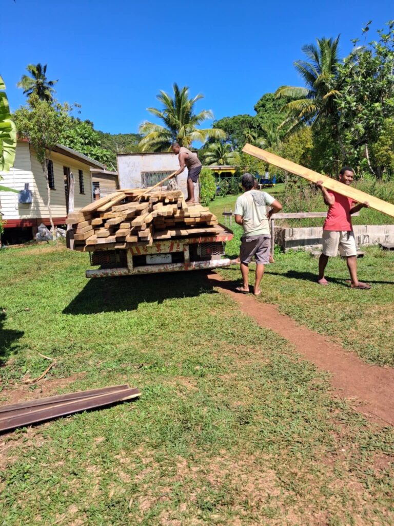 3 people load construction materials on a truck