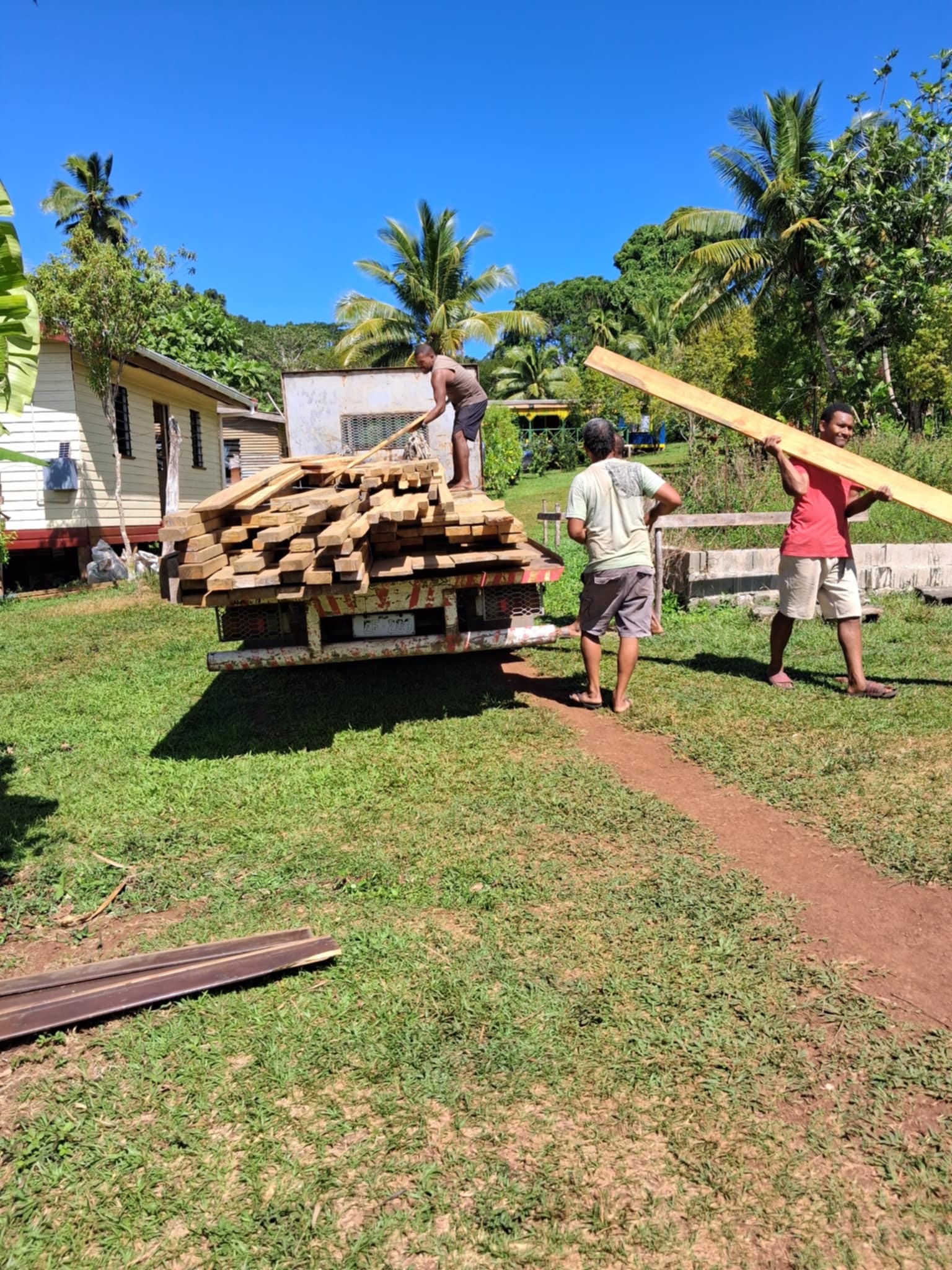 3 people load construction materials on a truck
