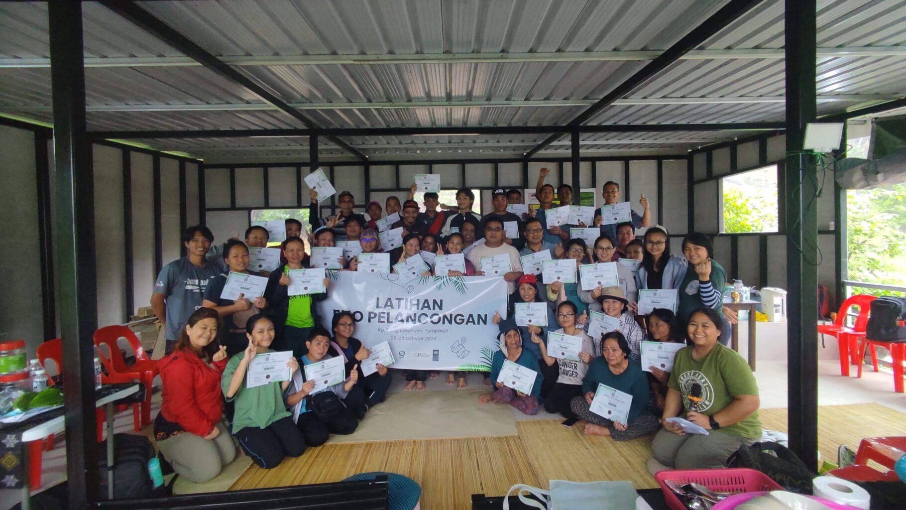 A group of people poses with certificates around a large banner