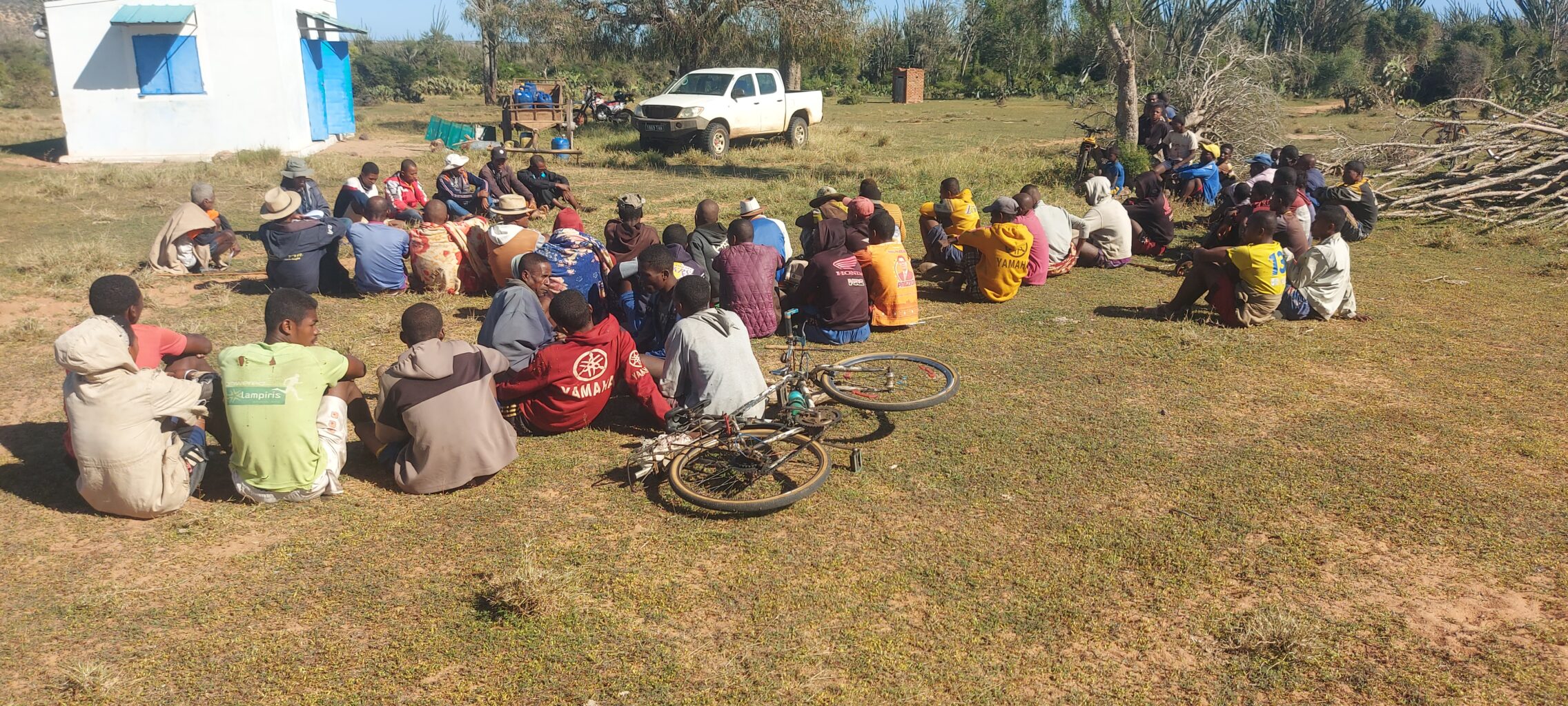 A group of people sit on the ground in a field