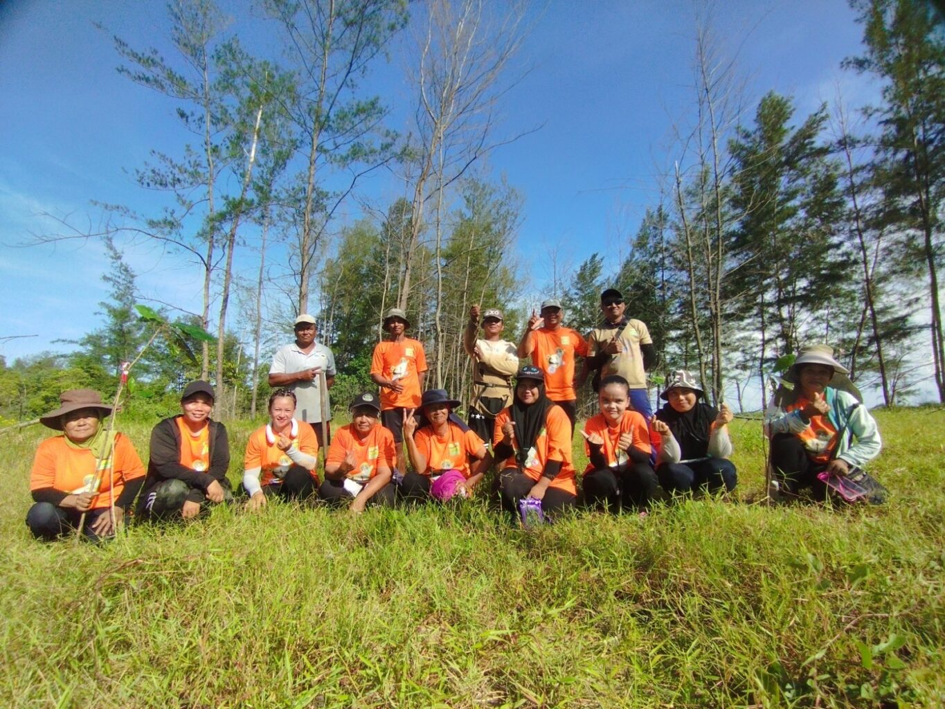 A group of people in orange shirts pose for the camera in a field