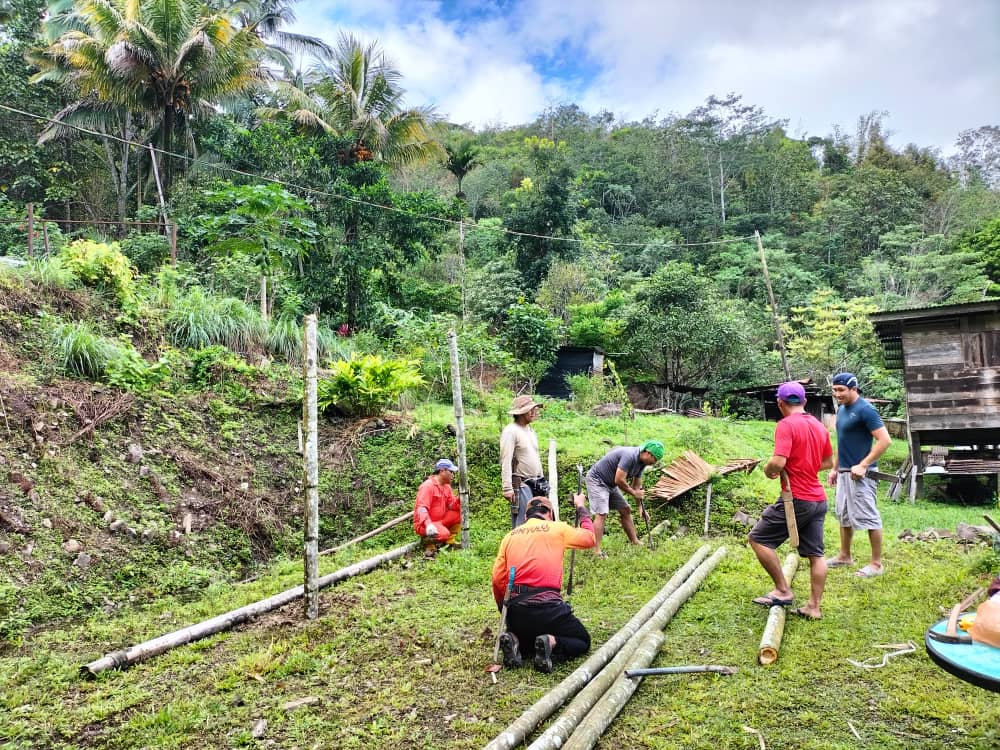 A group of people cuts wooden poles